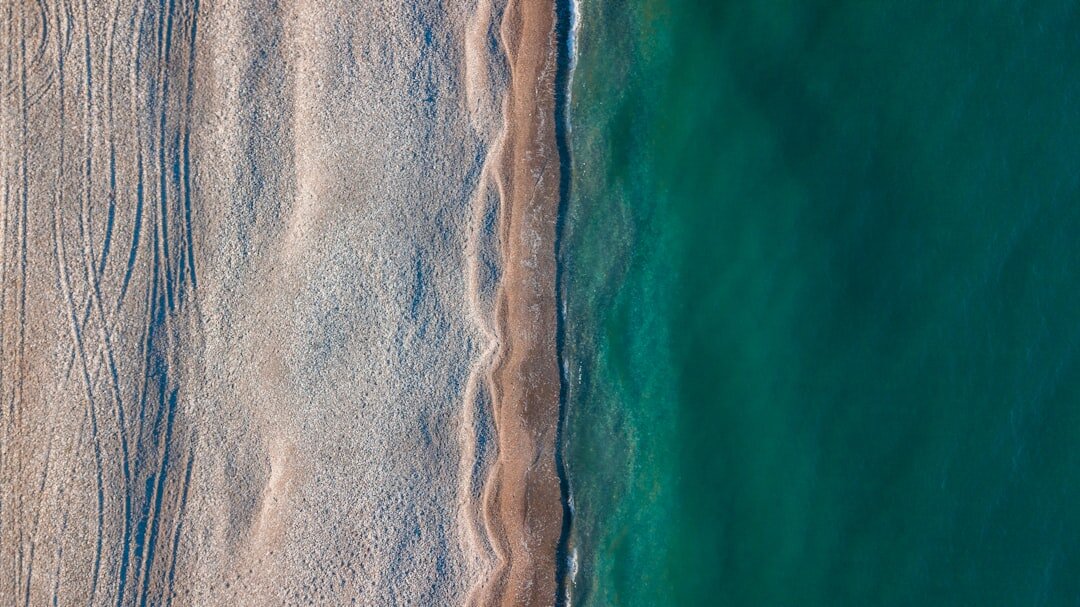 Aerial view of a golden sand coastline meeting turquoise ocean waters at sunset